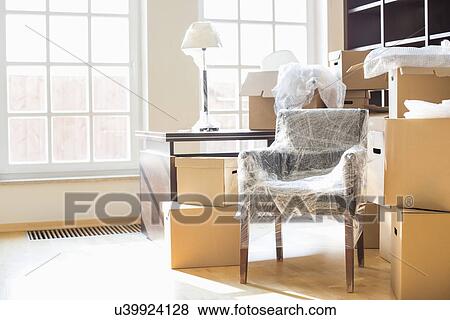 Stock Photo - Moving boxes and furniture in new home. Fotosearch