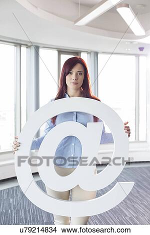 Portrait of beautiful businesswoman holding at sign in creative office View Large Photo Image Picture - Portrait of beautiful businesswoman holding at sign in creative office. Fotosearch