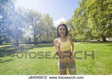 Stock Image - Portrait of beautiful fit woman jogging at park. Fotosearch