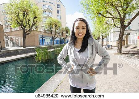 Portrait of beautiful fit woman standing by canal against buildings View Large Photo Image Stock Image - Portrait of beautiful fit woman standing by canal against buildings. Fotosearch