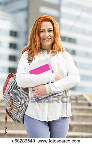 Stock Image - Portrait of beautiful student with textbooks at college campus. Fotosearch