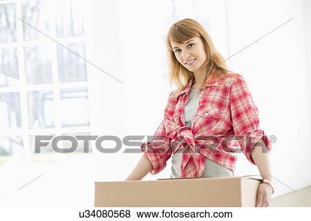Stock Photo - Portrait of beautiful woman carrying cardboard box. Fotosearch