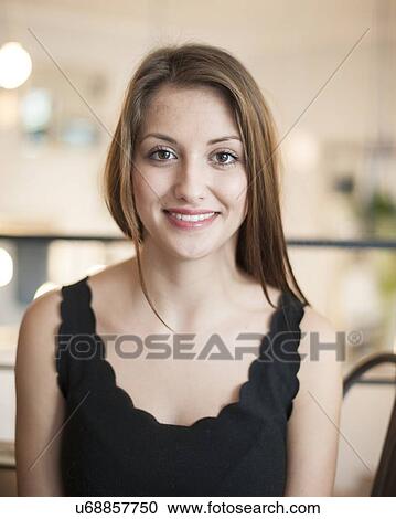 Stock Image - Portrait of beautiful young woman smiling at cafe. Fotosearch