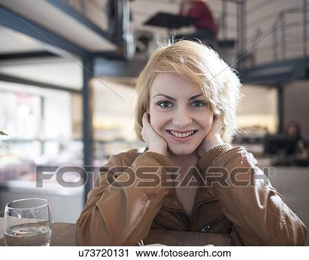 Stock Image - Portrait of beautiful young woman smiling in cafe. Fotosearch