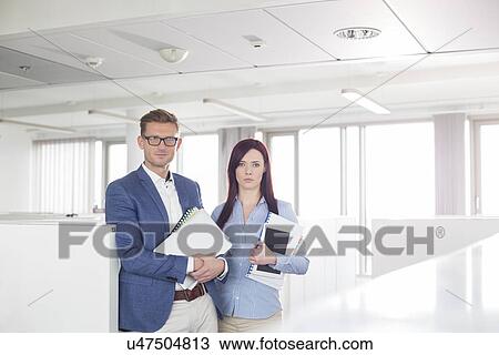 Stock Image - Portrait of confident business people standing in office. Fotosearch