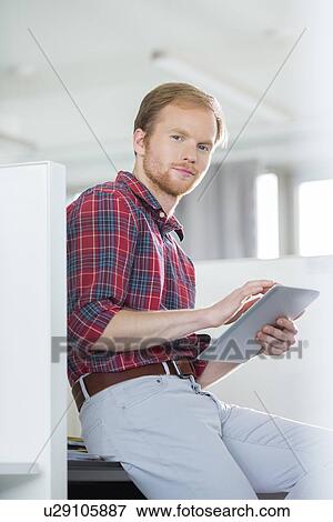Portrait of confident businessman using tablet PC in creative office View Large Photo Image Stock Photo - Portrait of confident businessman using tablet PC in creative office. Fotosearch