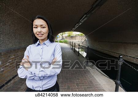 Stock Photo - Portrait of confident businesswoman standing arms crossed by canal. Fotosearch