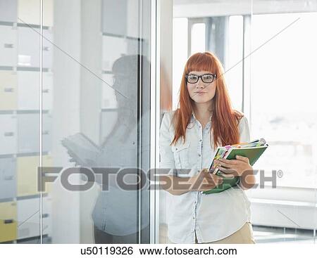 Portrait of confident businesswoman holding files in creative office View Large Photo Image Stock Photograph - Portrait of confident businesswoman holding files in creative office. Fotosearch