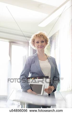 Portrait of confident businesswoman holding files in creative office View Large Photo Image Stock Photograph - Portrait of confident businesswoman holding files in creative office. Fotosearch