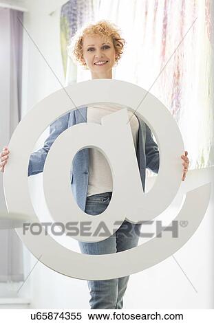 Portrait of confident businesswoman holding at sign in creative office View Large Photo Image Stock Photography - Portrait of confident businesswoman holding at sign in creative office. Fotosearch