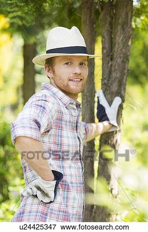 Portrait of confident gardener standing at plant nursery View Large Photo Image Stock Photo - Portrait of confident gardener standing at plant nursery. Fotosearch