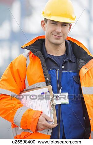 Portrait of confident mid adult man with clipboard in shipping yard View Large Photo Image Stock Image - Portrait of confident mid adult man with clipboard in shipping yard. Fotosearch