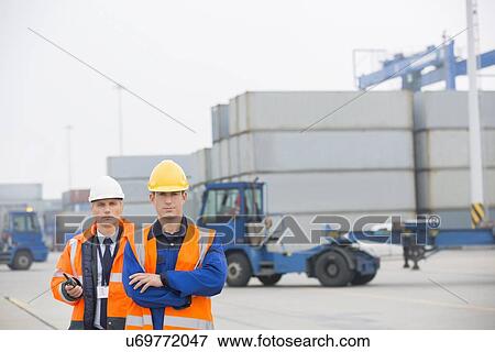Stock Photo - Portrait of confident workers standing in shipping yard. Fotosearch