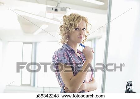 Portrait of creative businesswoman standing in front of presentation board in office View Large Photo Image Stock Photo - Portrait of creative businesswoman standing in front of presentation board in office. Fotosearch