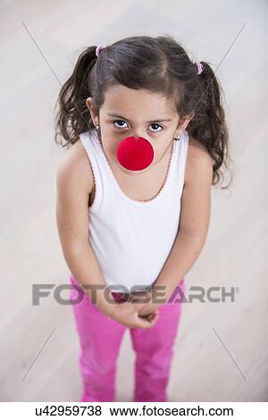 Stock Photo - Portrait of cute little girl wearing clown nose at home. Fotosearch