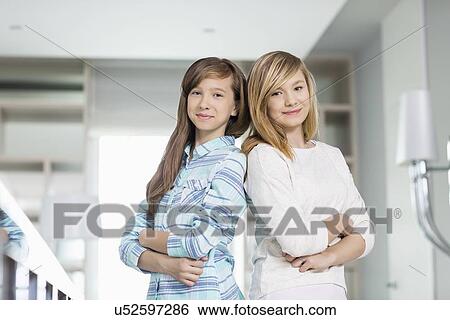 Portrait of cute sisters standing together at home View Large Photo Image Stock Photograph - Portrait of cute sisters standing together at home. Fotosearch