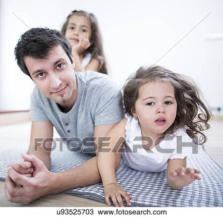 Portrait of father with daughters lying on blanket at home View Large Photo Image Stock Image - Portrait of father with daughters lying on blanket at home. Fotosearch