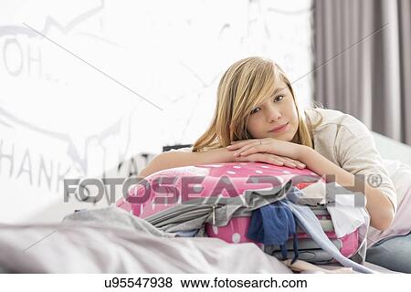 Portrait of girl relaxing on bulging suitcase at home View Large Photo Image Stock Photo - Portrait of girl relaxing on bulging suitcase at home. Fotosearch