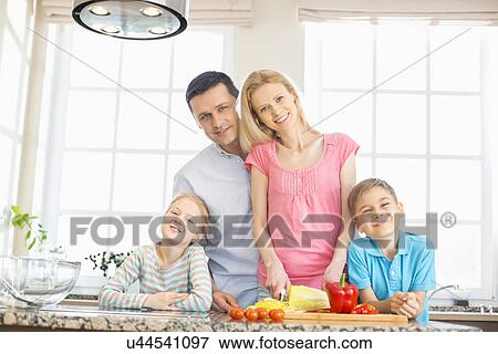 Portrait of happy family preparing food in kitchen View Large Photo Image Stock Photo - Portrait of happy family preparing food in kitchen. Fotosearch