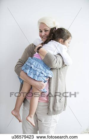 Portrait of happy grandmother carrying granddaughter at home View Large Photo Image Stock Image - Portrait of happy grandmother carrying granddaughter at home. Fotosearch