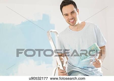 Stock Photo - Portrait of happy man painting his new house. Fotosearch