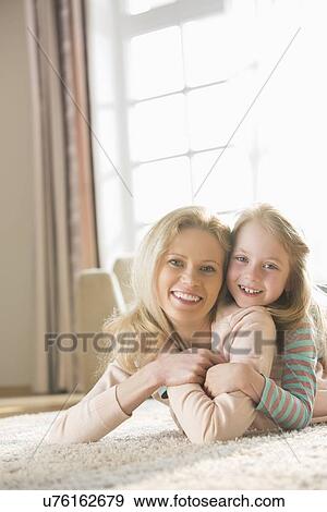 Portrait of happy mother and daughter lying on floor at home View Large Photo Image Stock Photo - Portrait of happy mother and daughter lying on floor at home. Fotosearch