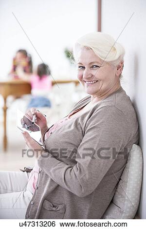 Stock Photograph - Portrait of happy senior woman using digital tablet with stylus at home. Fotosearch