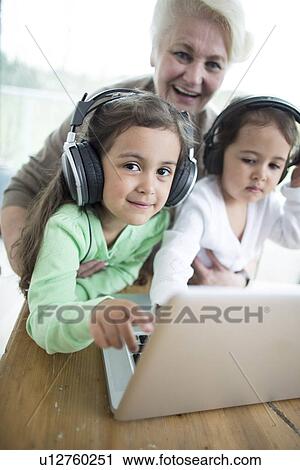 Portrait of happy senior woman with granddaughters listening to music while using laptop View Large Photo Image Stock Image - Portrait of happy senior woman with granddaughters listening to music while using laptop. Fotosearch