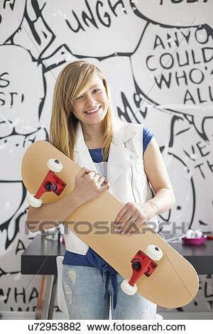 Portrait of happy teenage girl holding skateboard at home View Large Photo Image Stock Image - Portrait of happy teenage girl holding skateboard at home. Fotosearch