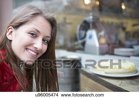 Picture - Portrait of happy woman by display cabinet in cafe. Fotosearch