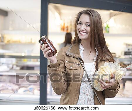 Stock Photo - Portrait of happy woman snacks and chocolate jar outside cafe. Fotosearch
