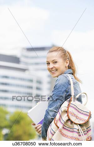 Stock Image - Portrait of happy young female student at college campus. Fotosearch
