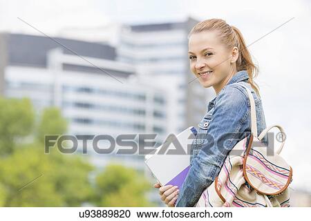 Stock Image - Portrait of happy young female student at college campus. Fotosearch