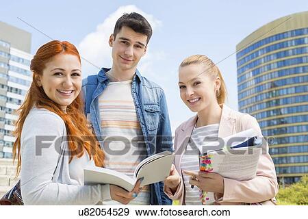 Stock Photo - Portrait of happy young university students studying outdoors. Fotosearch