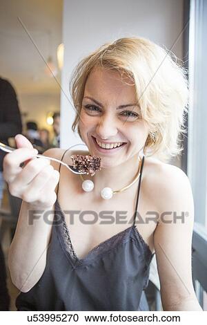 Portrait of happy young woman eating pastry in cafe View Large Photo Image Stock Image - Portrait of happy young woman eating pastry in cafe. Fotosearch