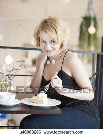 Portrait of happy young woman eating cake at cafe View Large Photo Image Stock Photograph - Portrait of happy young woman eating cake at cafe. Fotosearch