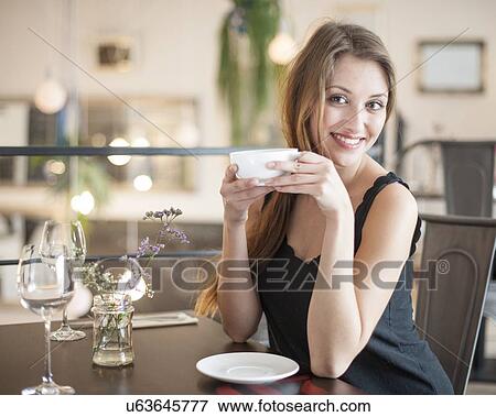 Portrait of happy young woman having coffee at restaurant View Large Photo Image Stock Photo - Portrait of happy young woman having coffee at restaurant. Fotosearch