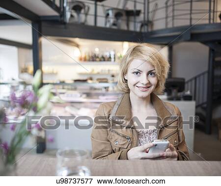 Portrait of happy young woman using cell phone in cafe View Large Photo Image Stock Photo - Portrait of happy young woman using cell phone in cafe. Fotosearch