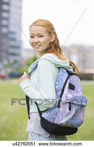 Stock Image - Portrait of happy young woman with backpack at college campus. Fotosearch