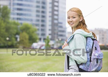 Stock Image - Portrait of happy young woman with backpack at college campus. Fotosearch