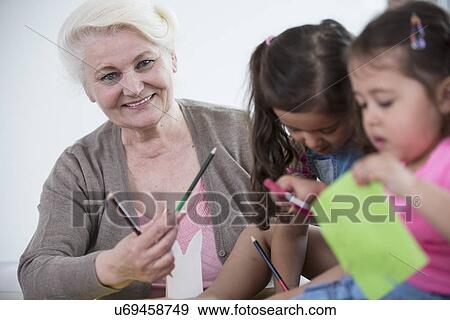 Portrait of senior woman helping granddaughters in making handicrafts at home View Large Photo Image Stock Photo - Portrait of senior woman helping granddaughters in making handicrafts at home. Fotosearch