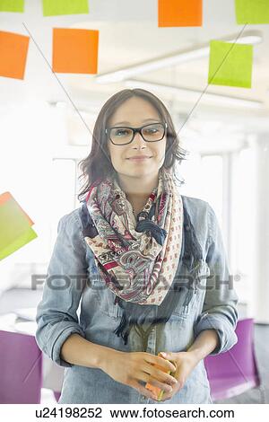 Portrait of smiling businesswoman standing by glass wall with sticky notes in office View Large Photo Image Stock Image - Portrait of smiling businesswoman standing by glass wall with sticky notes in office. Fotosearch