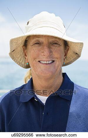 Stock Photograph - Portrait of smiling woman wearing hat on yacht. Fotosearch