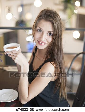 Portrait of smiling young woman having coffee at cafe View Large Photo Image Stock Photo - Portrait of smiling young woman having coffee at cafe. Fotosearch