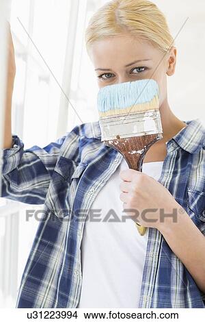 Portrait of woman holding paintbrush in front of face View Large Photo Image Picture - Portrait of woman holding paintbrush in front of face. Fotosearch
