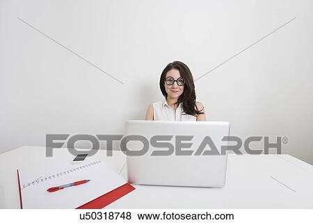Portrait of young businesswoman in nerd glasses with laptop at desk in office View Large Photo Image Stock Photo - Portrait of young businesswoman in nerd glasses with laptop at desk in office. Fotosearch