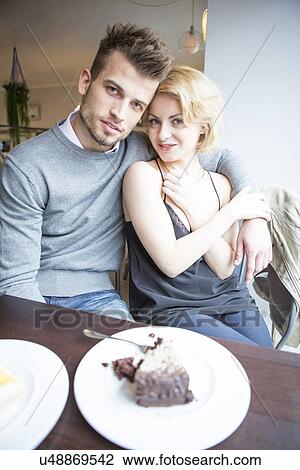 Stock Image - Portrait of young couple sitting at cafe table. Fotosearch