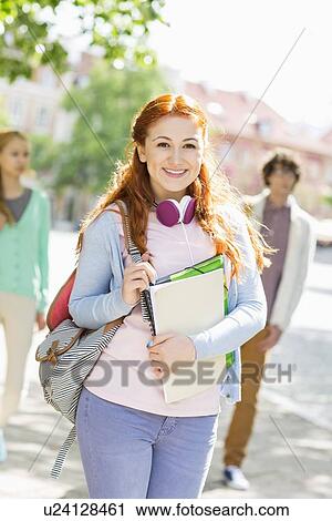 Portrait of young female student with friends in background on street View Large Photo Image Stock Image - Portrait of young female student with friends in background on street. Fotosearch
