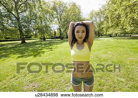 Stock Photo - Portrait of young fit woman stretching at park. Fotosearch