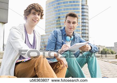 Stock Photo - Portrait of young male college students studying on steps against building. Fotosearch